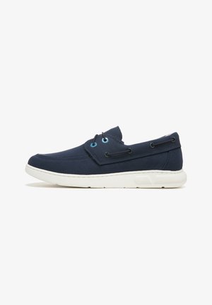 Marineblaue Segeltuch-Sneaker mit einer weißen Gummisohle, runder Schuhspitze, zwei Ösen und blauen Akzenten an den Schnürsenkeln und Nähten.