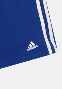Pantalones cortos deportivos Adidas azul con tres rayas blancas a lo largo del costado y el logo de Adidas cerca del dobladillo.