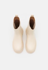Stivaletti beige realizzati in materiale liscio, con punta arrotondata, pannelli laterali elastici e una suola in gomma resistente con una leggera scolpitura.