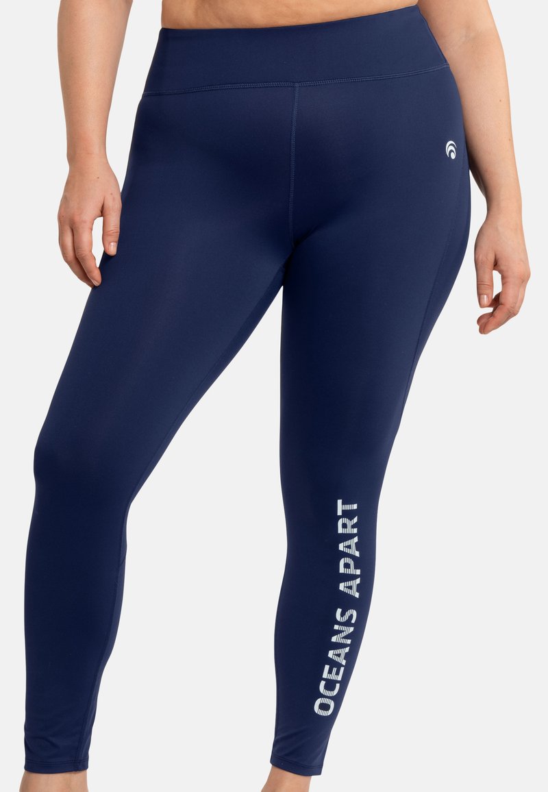 Leggings navy realizzati in tessuto elastico, con vita alta e la frase "OCEANS APART" stampata in bianco lungo il lato.