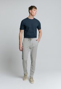 Marine gestreept t-shirt, lichtbeige jogpants met aantrekkoord en lichte schoenen. Slim fit, katoenmateriaal, gladde textuur en subtiele merkdetail.