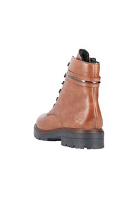 Bottine en cuir marron avec une finition texturée, semelle en caoutchouc noir robuste, accents métalliques et fermeture à lacets noirs.