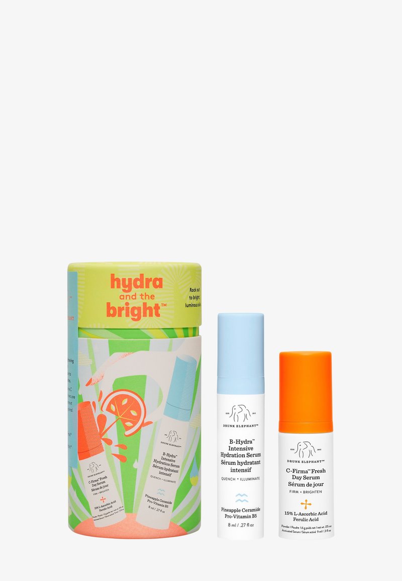 Set includes two serums in light blue and orange bottles, housed in a colorful cylindrical container with tropical graphics and text.