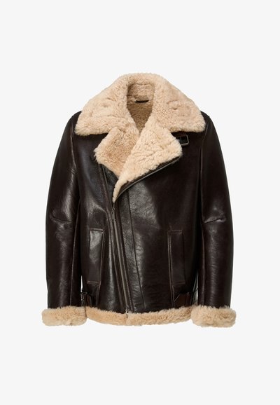 Veste en cuir marron avec col et doublure en peau lainée beige. Comprend une fermeture éclair, deux poches avant et des sangles latérales ajustables.