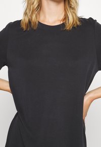 Svart kortärmad t-shirt med rund halsringning, tillverkad av mjukt tyg, med avslappnad passform och subtil textur utan synliga mönster eller dekorationer.