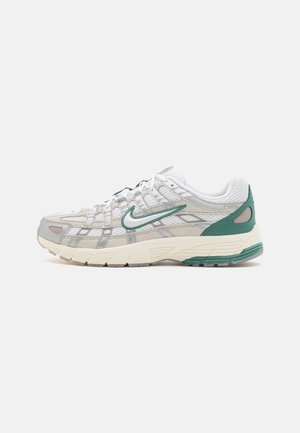 Chaussure de sport blanche et grise avec des accents verts et un logo Nike swoosh vert sur le côté, montrée de côté extérieur sur fond blanc.