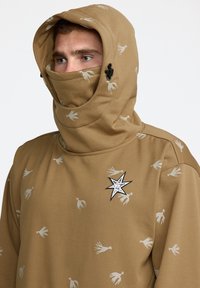 Sweat-shirt à capuche marron avec des motifs d'oiseaux, capuche ajustable et un patch en forme d'étoile sur la poitrine. Texture douce, manches longues.
