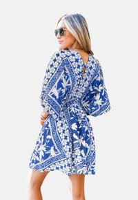 Abito blu con motivo floreale, con vita aderente, maniche corte e dettaglio a chiave sulla schiena. Realizzato in tessuto leggero, offre una silhouette fluida.