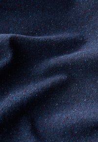 Texturiertes marineblaues Gewebe mit Sprenkeln in Rot und Blau. Das gerippte Design hebt die Oberflächenstruktur hervor und sorgt für ein reichhaltiges taktiles Erscheinungsbild.