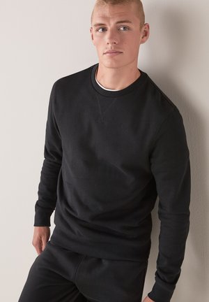 Czarny sweter z miękkiego materiału, z okrągłym dekoltem, długimi rękawami i luźnym krojem. Gładka tekstura z minimalnymi detalami.