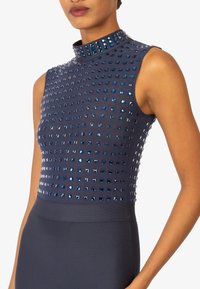 Marineblaue ärmellose Kleid mit hohem Kragen, das ein tailliertes Oberteil mit quadratischen, reflektierenden blauen Nieten zeigt. Glatter Unterbereich.