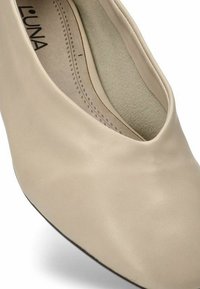 Zapato de piel beige con puntera redondeada y corte bajo en los lados. Forro interior suave y textura lisa, diseñado para la comodidad.