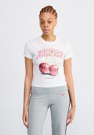 T-shirt bianco a maniche corte con la scritta rossa "JORDAN" e grafiche di ciliegie rosa. Abbinato a pantaloni sportivi grigi con il logo Nike.