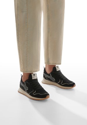 Scarpe sportive nere con accenti grigi, design con lacci e suola testurizzata. Indossate con pantaloni chiari, leggermente accorciati.
