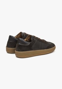 Brązowe zamszowe i skórzane sneakersy z gumową podeszwą, z teksturowanymi akcentami i brązowymi sznurowadłami. Posiadają wyściełany kołnierz i szycie na bocznych panelach.
