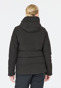 Veste en duvet noire avec capuche, présentant un design matelassé et des poignets élastiques, vue de l'arrière. Le matériau semble lisse et isolant.