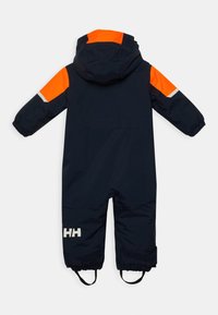 Marine waterdichte sneeuwpak met oranje accenten op de schouders en capuchon, voorzien van elastische manchetten en een reflecterende strip. Merkmotief op het been.