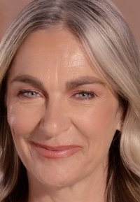 Close-up van het gezicht van een vrouw met lichtgrijs haar en blauwe ogen, met een gladde huid, subtiele rimpels en een natuurlijke lipkleur.