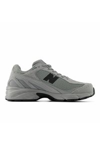 Scarpa sportiva grigia con tomaia in mesh, collo imbottito e logo nero. La suola è sagomata per offrire comfort e presenta una superficie texturizzata.