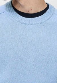 Hellblauer Strickpullover mit rundem Hals, der einen dunkelblauen gerippten Kragen aufweist. Glatte Textur und gleichmäßiges Stichmuster überall.
