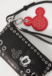 Zwarte leren portemonnee met zilveren studs, een Mickey Mouse ontwerp en een rode keychain met studs in de vorm van Mickey's hoofd.