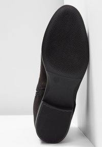 Semelle de chaussure noire avec un motif ondulé à l’avant-pied et des rainures horizontales au talon, taille de chaussure indiquée comme 37.