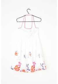 Biała sukienka na ramiączkach z różowymi paskami, ozdobiona kwiatowym wzorem w kolorach pomarańczowym, różowym i fioletowym wzdłuż dołu, wisząca na czarnym wieszaku.