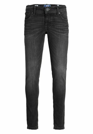 Chaleco de forro polar negro sobre una sudadera con capucha crema, combinado con vaqueros oscuros y zapatillas negras. El chaleco tiene un acabado texturizado con bolsillos.