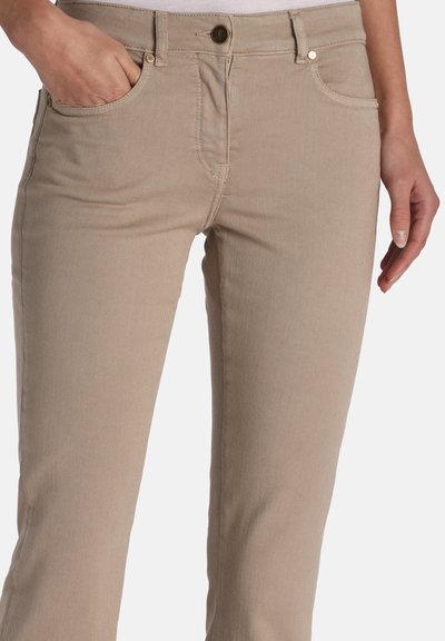 Bež bombažne hlače s pravo prileganjem, sprednjimi žepi in subtilnimi podrobnostmi šivov. Na pasu imajo detajle z zlatim tonom.