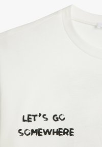 Weißes Baumwoll-T-Shirt mit schwarzem, handgezeichnetem Text, der "LASST UNS WOANDERS HIN GEHEN" sagt. Rundhalsausschnitt mit kurzen Ärmeln und weichem Material.