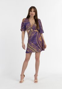 Violetti mekko, jossa on leikkauksia, lyhyet puffihihat ja kultaiset kuviot. Kangas on sileä ja siinä on kevyt kiilto.