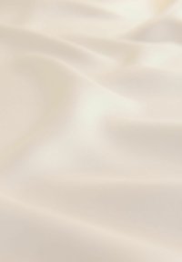 Ljust beige tyg med en jämn, satinliknande textur, som har mjuka veck och en subtil lyster över ytan.