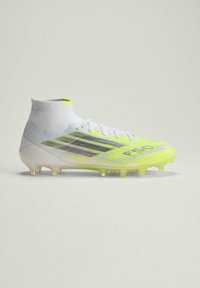 Λευκό και νέον κίτρινο ποδοσφαιρικό παπούτσι με περιλαίμιο αστραγάλου που μοιάζει με κάλτσα και μαύρες ρίγες, απεικονισμένο σε ουδέτερο φόντο.