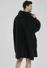 Felpa nera oversized con cappuccio, caratterizzata da una texture morbida, un ampio cappuccio e una vestibilità ampia. Arriva a metà coscia con spalle scese per un maggior comfort.