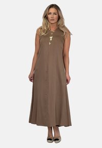 Brązowa maksidługa sukienka bez rękawów z suwakiem z przodu, gładki materiał, rozszerzana spódnica oraz złoty naszyjnik jako akcent. 