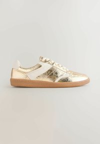 Gold metallic sneakers with white accents, rubber sole, and textured finish. Features classic lace-up design and stitched detailing.