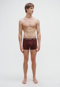 Vinröda boxershorts med svart elastisk midjeresår med "JACK & JONES"-logotyp. Slät tyg, kroppsnära passform, minimala sömdetaljer.