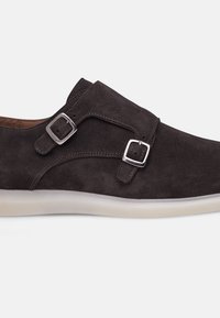 Chaussures en suède gris avec des sangles à double boucle, design cintré et semelle en caoutchouc. Présente des coutures contrastantes et une doublure intérieure lisse.