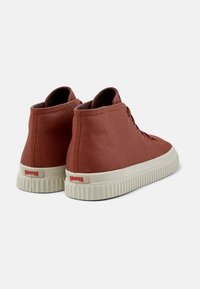 Sneakers w kolorze rdzy z wysoką cholewką, z teksturowanej tkaniny, kremową gumową podeszwą i wyraźnym logo Camper z tyłu.