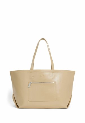 Sac à main en cuir beige avec double poignée, poche avant zippée et petit logo embossé au-dessus de la poche sur fond blanc uni.