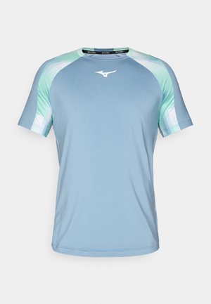 Lys blå atletisk skjorte lavet af glat stof. Har raglanærmer med grønne og mønstrede detaljer. Hvidt logo på brystet.