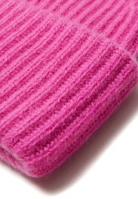 Gebreide roze wollen muts met een ribbelstructuur, met verticale lijnen en een zachte, donzige uitstraling. Compact ontwerp met een ronde vorm.