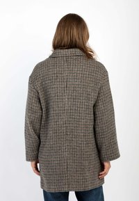 Cappotto marrone a quadri con vestibilità ampia, rever larghi e maniche lunghe. Texture morbida, design di lunghezza media e silhouette dritta.