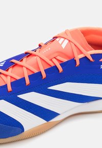 Scarpa sportiva sintetica blu con accenti arancioni, superficie texturizzata, strisce bianche e lacci in tono. Presenta un interno imbottito e suola in gomma.