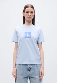 Ανοιχτό μπλε κοντομάνικο μπλουζάκι κατασκευασμένο από βαμβάκι. Διαθέτει τετράγωνο γραφικό σε ανοιχτό μπλε με τα γράμματα "cK" σε λευκό.