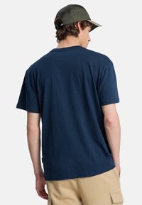 Navyblå t-shirt lavet af tekstureret stof, med rund hals og korte ærmer. Bæres med khaki cargo shorts.