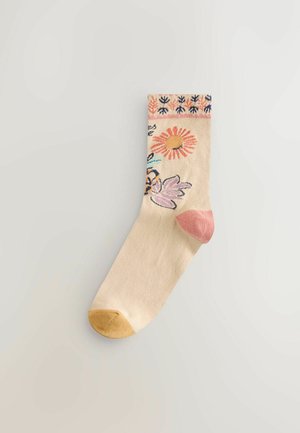 Kniestrümpfe aus beigem Baumwollstoff mit Blumenmustern in Pink, Gelb und Blau. Rosa Fersen- und gelbe Zehenakzente. Dekoratives Bündchenmuster.