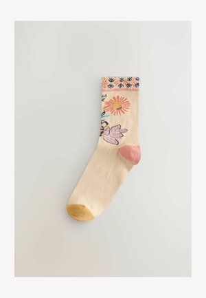 Kniestrümpfe aus beigem Baumwollstoff mit Blumenmustern in Pink, Gelb und Blau. Rosa Fersen- und gelbe Zehenakzente. Dekoratives Bündchenmuster.