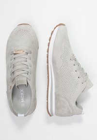 Baskets en daim gris clair avec un design perforé, fermeture à lacets, semelle extérieure en caoutchouc et une semelle intermédiaire blanche. Ornées d'un logo métallique.