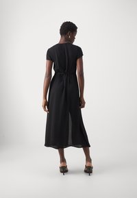 Black, mid-length dress with short sleeves, lightweight fabric, waist tie, and a back slit for ventilation. Minimalist design with clean lines.